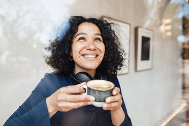 Happy woman with coffee cup seen through glass at cafe - JOSEF11881