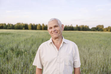 Smiling senior farmer standing in farm - EYAF02044