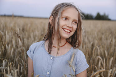 Lächelndes Mädchen inmitten von Feldfrüchten auf einem Bauernhof - EYAF02066
