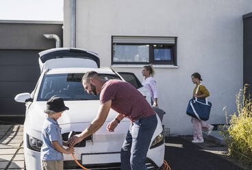 Vater und Sohn laden Elektroauto für Familienurlaub - UUF27079