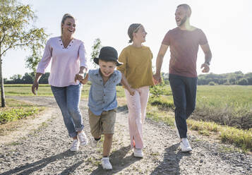 Happy familiy holding hands walking through nature - UUF27106