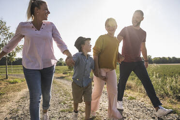 Happy familiy holding hands walking through nature - UUF27107