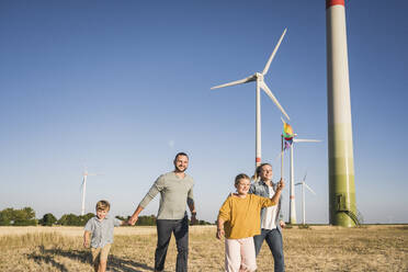Optimistische Familie, die im Windpark spazieren geht Tochter trägt buntes Windrad - UUF27112