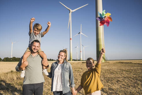Optimistische Familie, die im Windpark spazieren geht Tochter trägt buntes Windrad - UUF27113