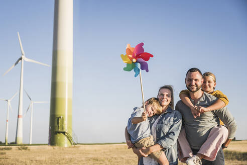 Optimistische Familie steht im Wind Park Sohn trägt bunte Windrad - UUF27120