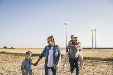 Selbstbewusste Familie spaziert händchenhaltend durch den Windpark - UUF27122