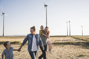 Selbstbewusste Familie spaziert händchenhaltend durch den Windpark - UUF27123