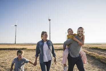 Selbstbewusste Familie spaziert händchenhaltend durch den Windpark - UUF27124