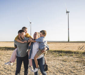 Selbstbewusste Familie mit Kindern im Windpark stehend - UUF27126