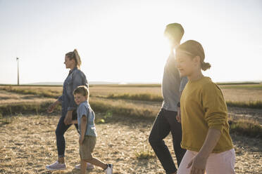 Confident family walking through wind park holding hands - UUF27133