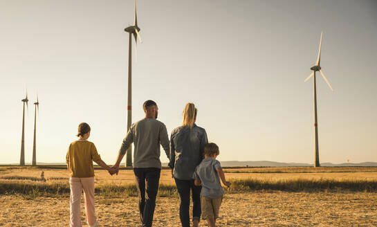 Selbstbewusste Familie spaziert händchenhaltend durch den Windpark - UUF27134