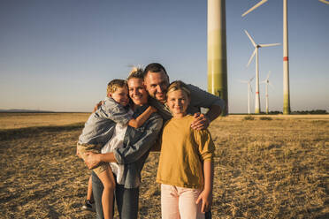 Glückliche Familie im Windpark, die ihre Kinder umarmt - UUF27142