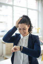 Stressed businesswoman looking at smart watch - JOSEF11955