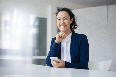 Smiling businesswoman holding mobile phone - JOSEF11972