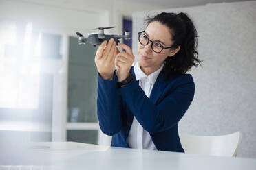 Businesswoman with eyeglasses looking at drone - JOSEF11976