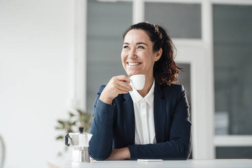 Glückliche Geschäftsfrau hält Kaffeetasse zu Hause - JOSEF12020