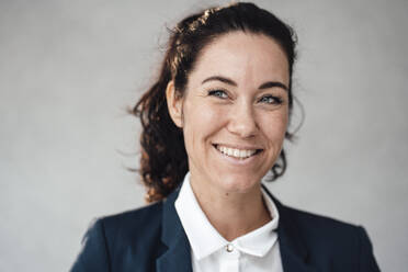 Smiling businesswoman in front of gray wall - JOSEF12024