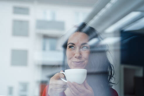 Smiling woman having coffee seen through glass - JOSEF12056