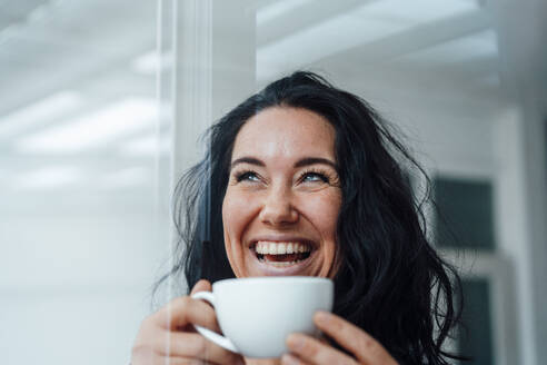 Cheerful woman having coffee seen through glass - JOSEF12058