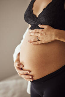 Hände einer schwangeren Frau berühren den Bauch zu Hause - JHAF00152