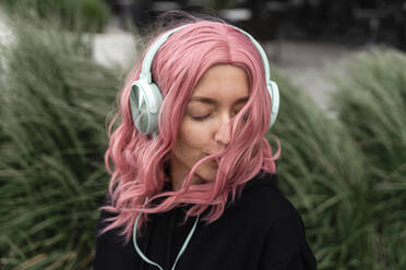 Young woman with eyes closed listening music through headphones - TOF00021