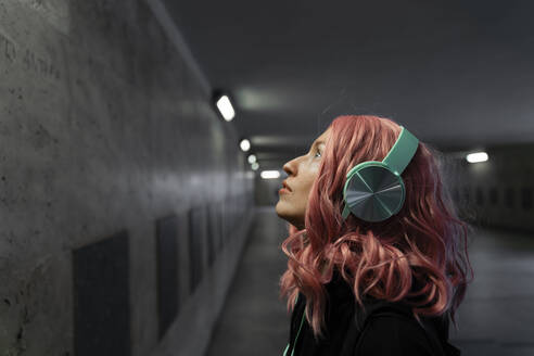 Woman with pink dyed hair listening music through headphones - TOF00024