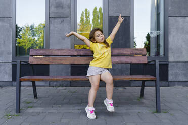 Mädchen mit erhobenen Armen auf einer Bank sitzend - TOF00036