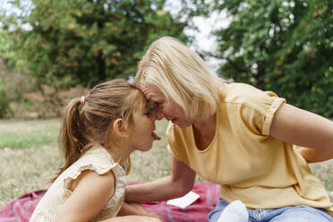 Playful girl having fun with grandmother at park - TOF00050