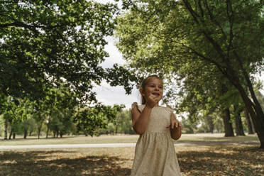 Glückliches Mädchen inmitten von Bäumen im Park - TOF00052