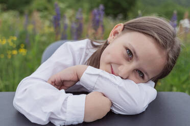 Smiling girl leaning on desk at meadow - OSF00763