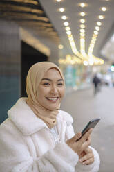 Lächelnde junge Frau mit Mobiltelefon - AMWF00293