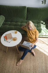 Freelancer working on laptop in living room at home - SVKF00521