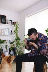 Man photographing pet dog at home - ASGF02674