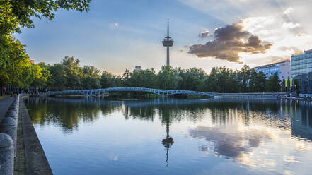 Germany, North Rhine-Westphalia, Cologne, MediaPark lake at dusk with Colonius tower in background - MHF00632