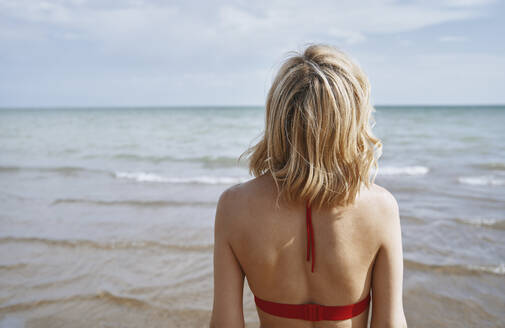 Frau mit blondem Haar schaut aufs Meer - AZF00420