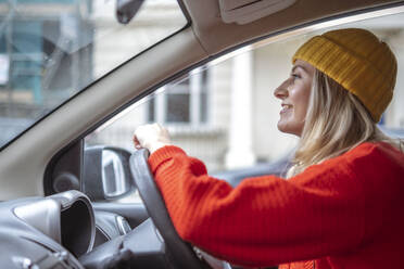 Lächelnde Frau mit Strickmütze fährt Auto - AMWF00319