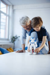 Boy playing with robot model by grandfather at home - JOSEF12094