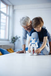 Junge spielt mit Robotermodell von Großvater zu Hause - JOSEF12094