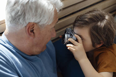 Junge fotografiert seinen Großvater mit der Kamera zu Hause - JOSEF12095