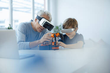 Großvater und Enkel mit VR-Brille beobachten Robotermodell zu Hause - JOSEF12109
