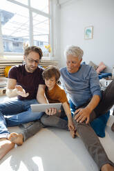 Mature man sharing tablet PC with son and father at home - JOSEF12131