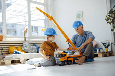 Junge spielt mit Kranspielzeug bei seinem Großvater im Wohnzimmer - JOSEF12135