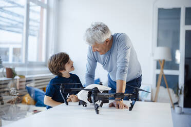 Großvater und Enkel unterhalten sich mit einer Drohne auf dem Wohnzimmertisch - JOSEF12152