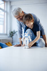 Boy with robot model by smiling grandfather at home - JOSEF12158