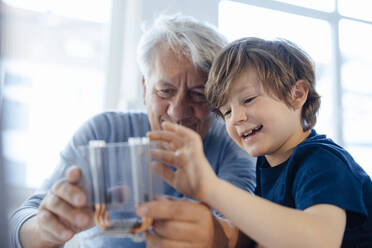 Smiling grandson and grandfather examining heating module at home - JOSEF12160