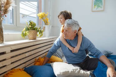 Grandson and grandfather looking through window at home - JOSEF12175