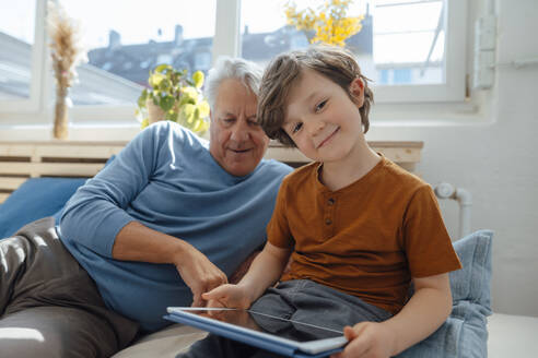 Lächelnder Junge mit Tablet-PC bei seinem Großvater zu Hause - JOSEF12177