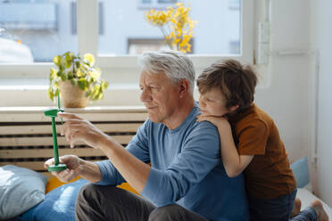 Grandfather analyzing wind turbine model by grandson at home - JOSEF12181