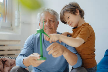 Lächelnder Großvater und Enkel bei der Analyse eines Windradmodells zu Hause - JOSEF12183