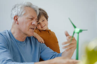 Großvater und Enkel analysieren das Modell einer Windkraftanlage zu Hause - JOSEF12184